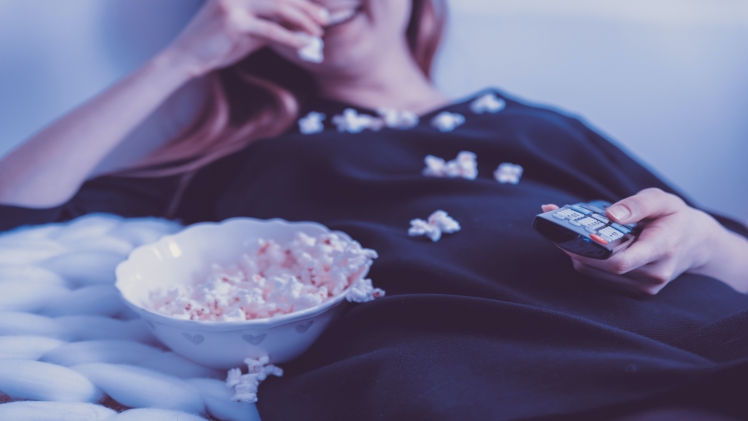 a woman eating popcorn and watching a movie